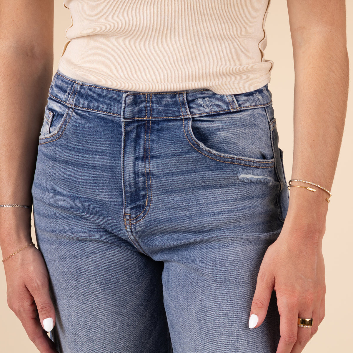 Close-up of the jeans&#39; raw hem and light distressing along the edge, showing the textured denim fabric and slight fade in color.