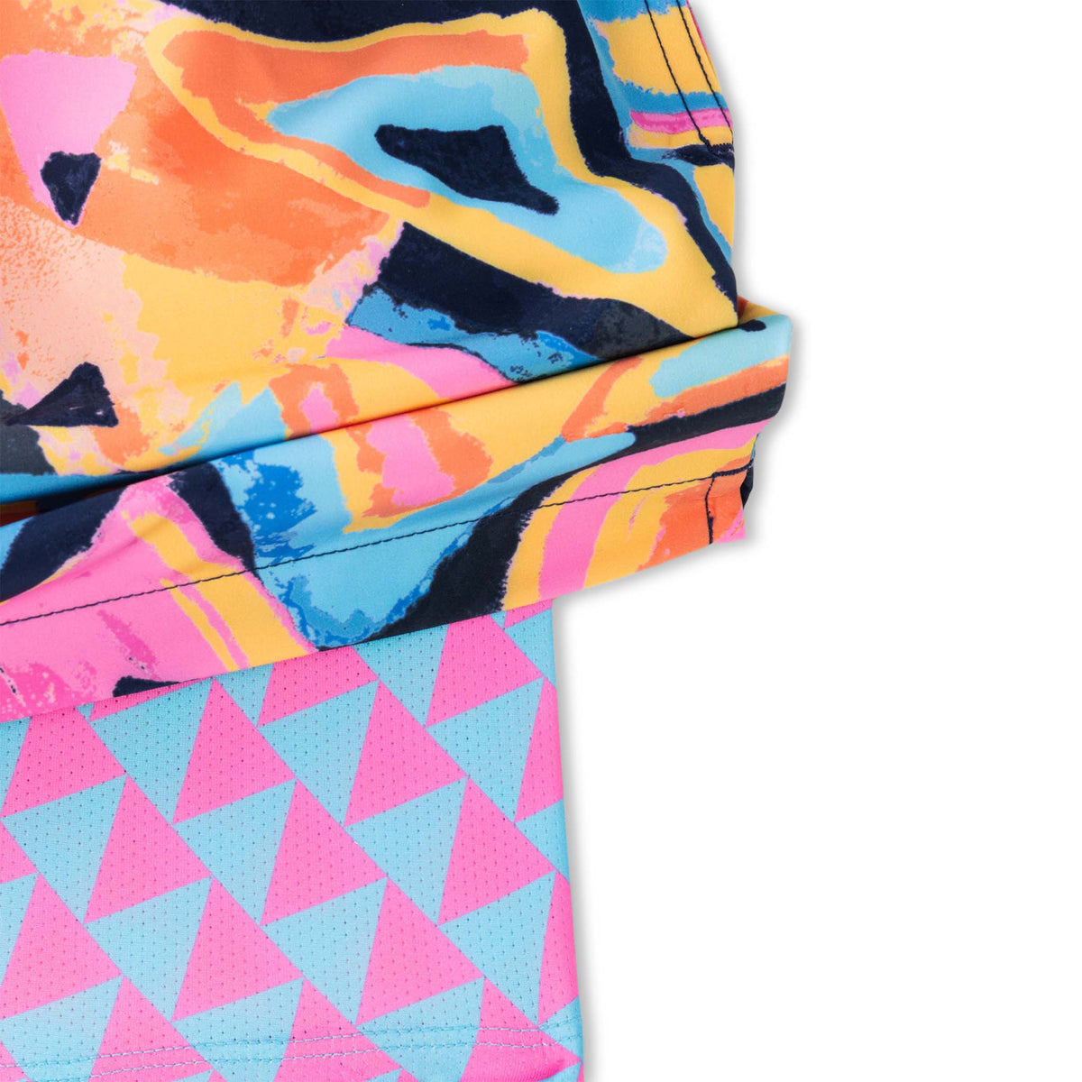 en’s swim trunks featuring a bold, abstract geometric print in bright colors including pink, orange, yellow, blue, and navy. The design includes layered triangles and brushstroke-style shapes. The shorts have a white drawstring at the elastic waistband and include a built-in liner with a blue and pink triangle pattern peeking out from the leg opening.