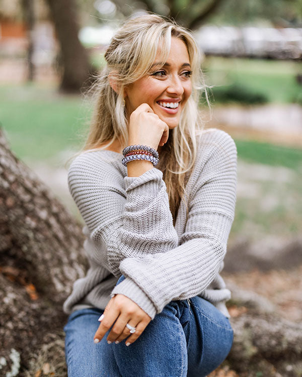 woman sitting on a tree showing off the fall teleties collection
