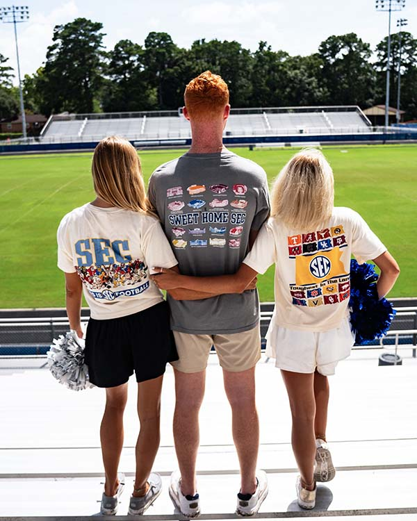 three people standing in football bleachers wearing SEC t-shirts