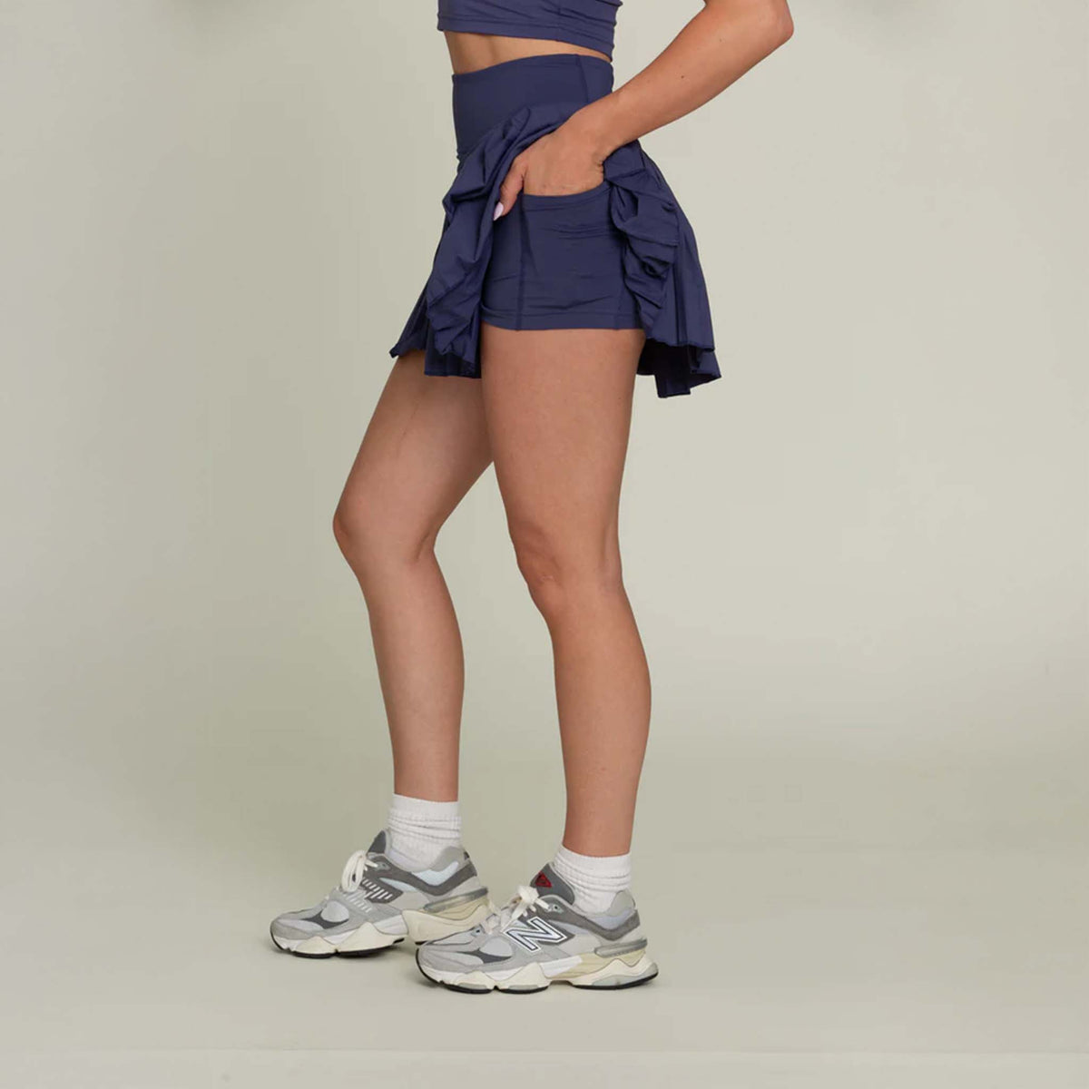 Side view of the pleated tennis skort highlighting the flared pleats and fitted waistband, designed for easy movement.