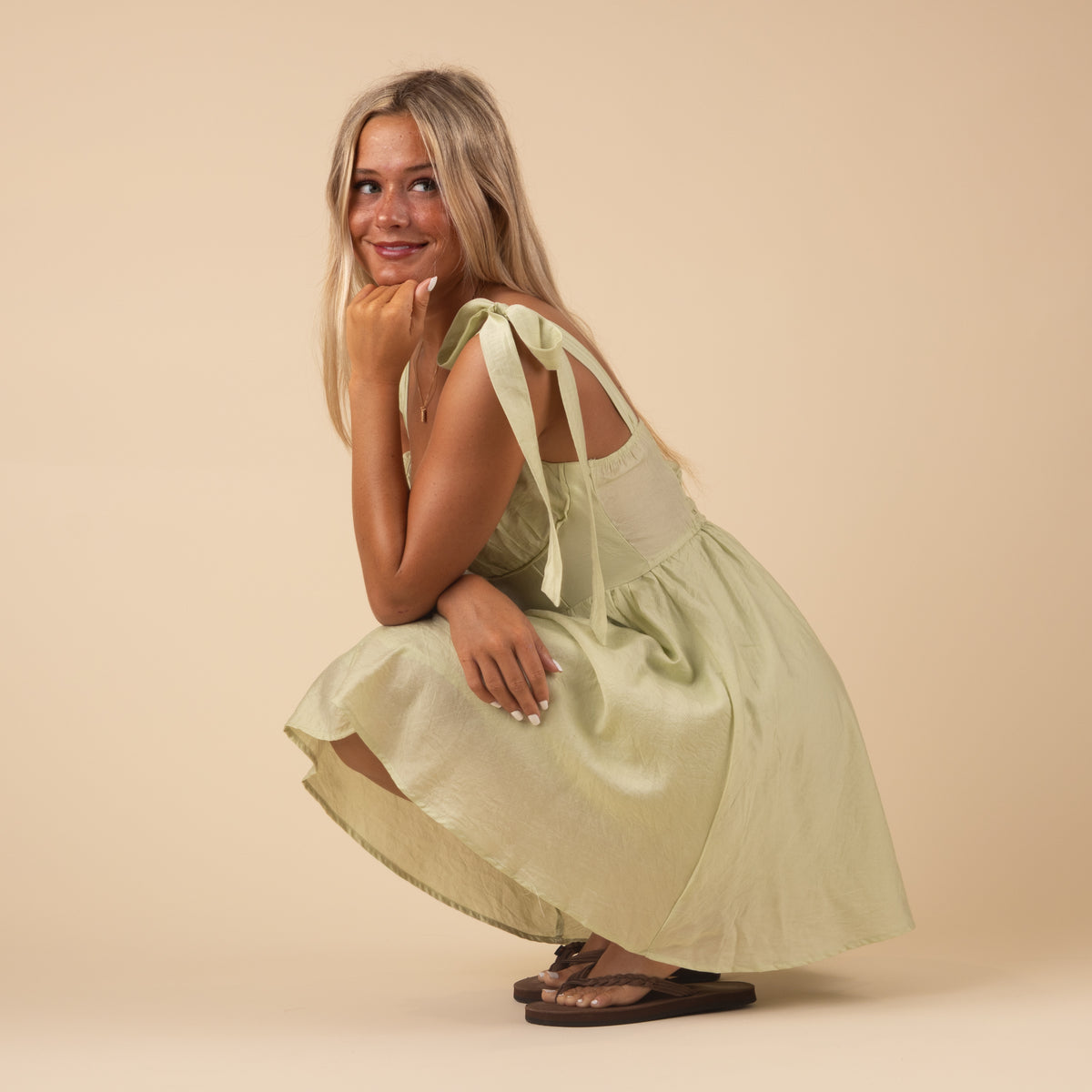 Woman wearing a Sleeveless Corset A-Line Knee length dress, Color Sage green, Sizes S-L. 
This dress features bows sewn on the shoulder of each strap adding a sweet, feminine detail!