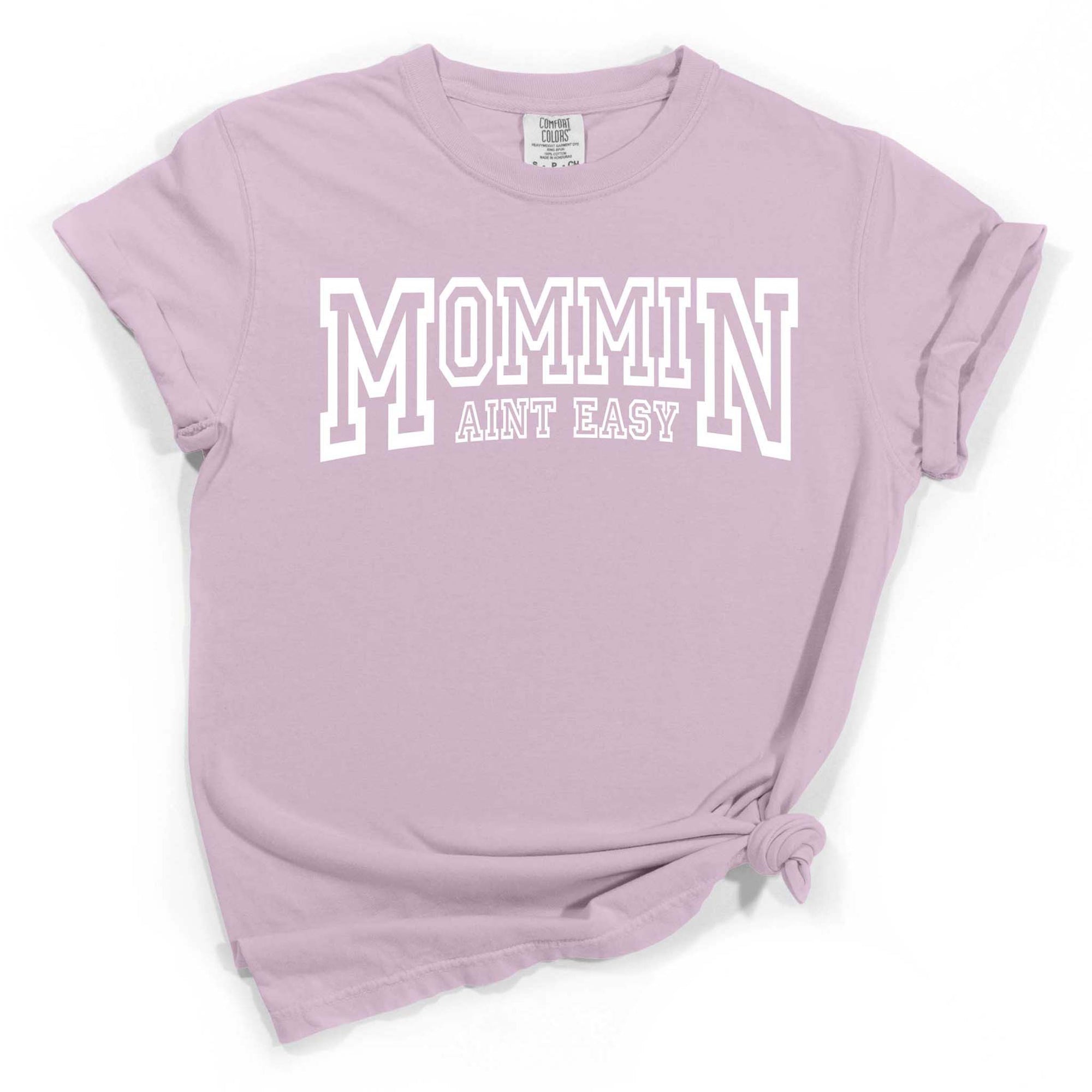 Mommin Aint Easy Graphic T-Shirt – A soft cotton short-sleeve tee featuring the playful phrase 'Mommin Aint Easy' in bold, stylish lettering. Classic crew neckline and relaxed fit, perfect for comfortable, everyday wear.