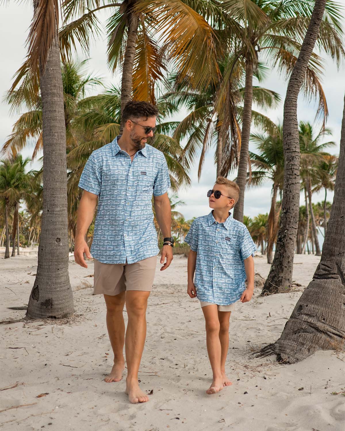 dad and sun walking down a beach in matching shirts