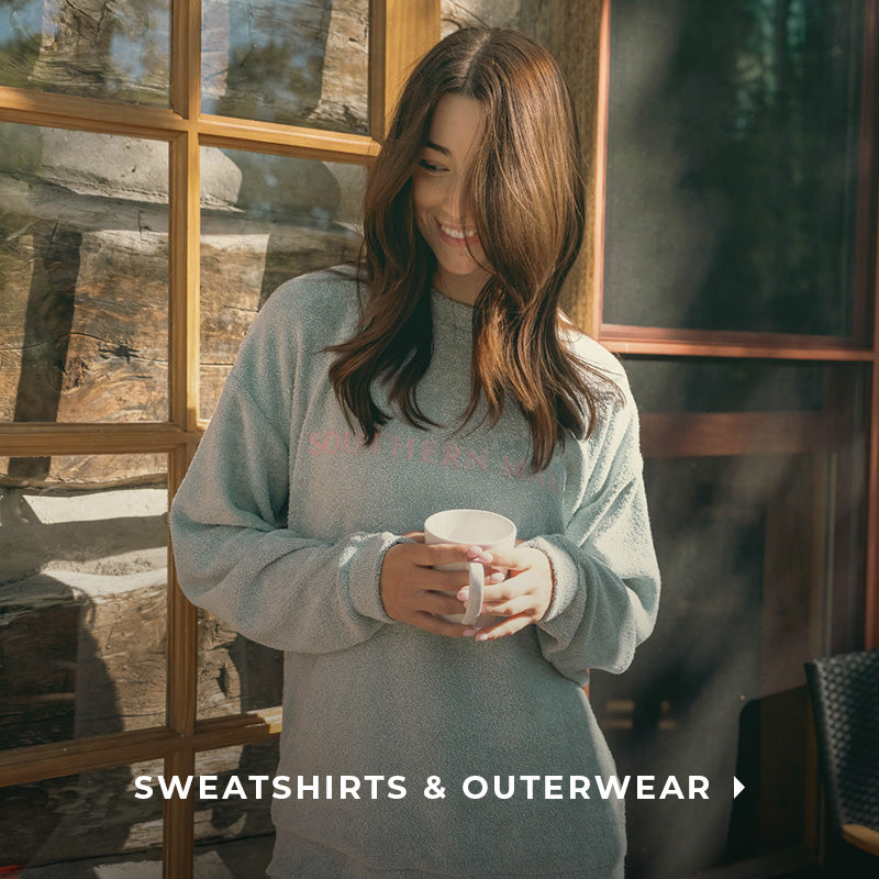 woman holding a coffee cup outside of a cabin