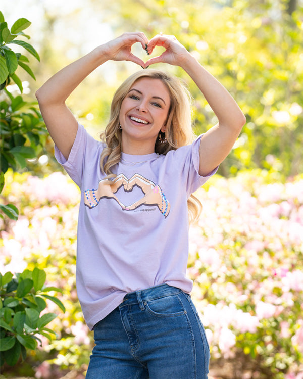 woman posing for a photo with heart hands