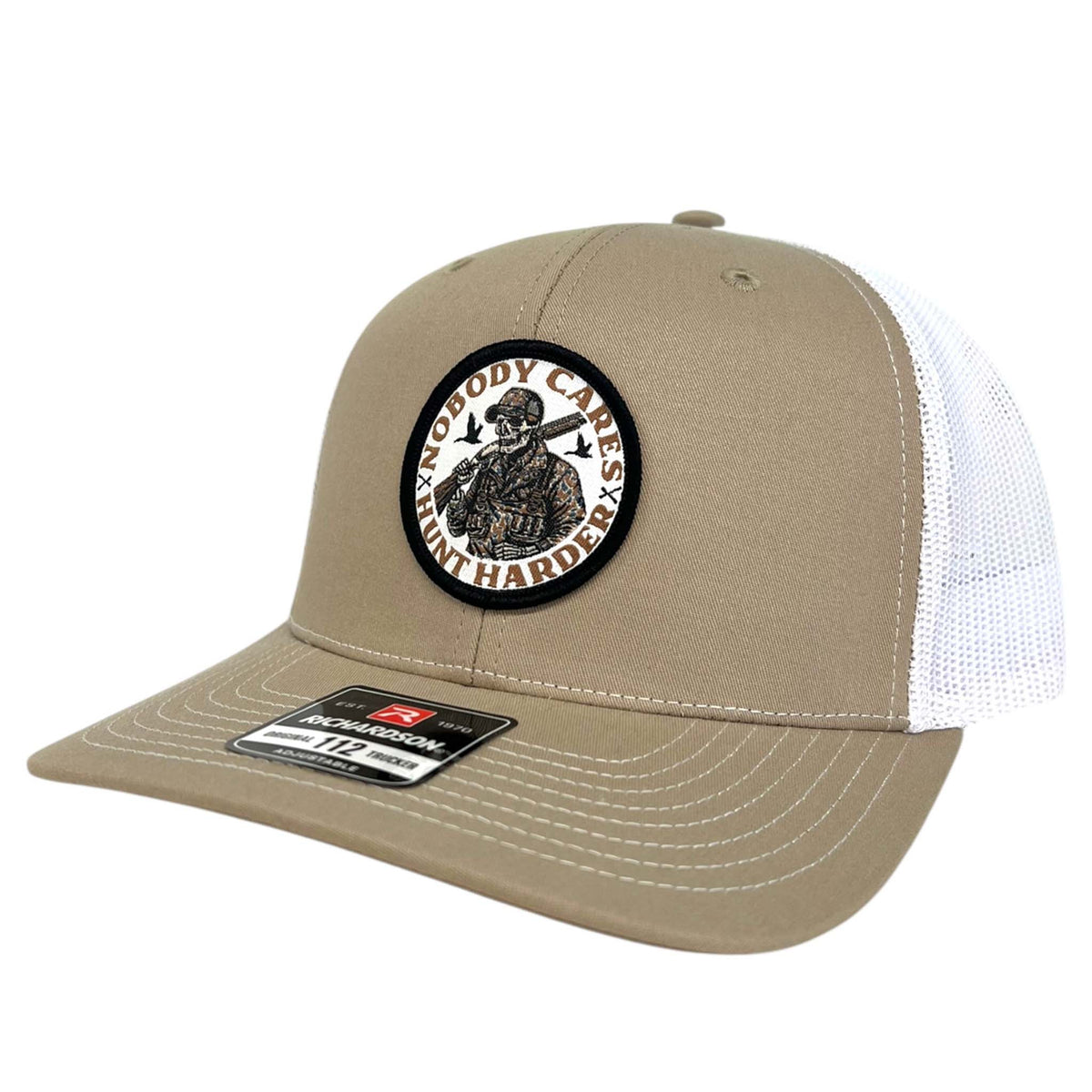 Good Ole Boys Adjustable Trucker Hat, color khaki and white. This hat features a patch sewn on the front with a skeleton wearing camouflage hunting gear and the words &quot;Nobody cares, Hunt Harder&quot; around the design. Adjustable snapback closure, soft mesh backing, mid-profile, pre-curved PE visor.